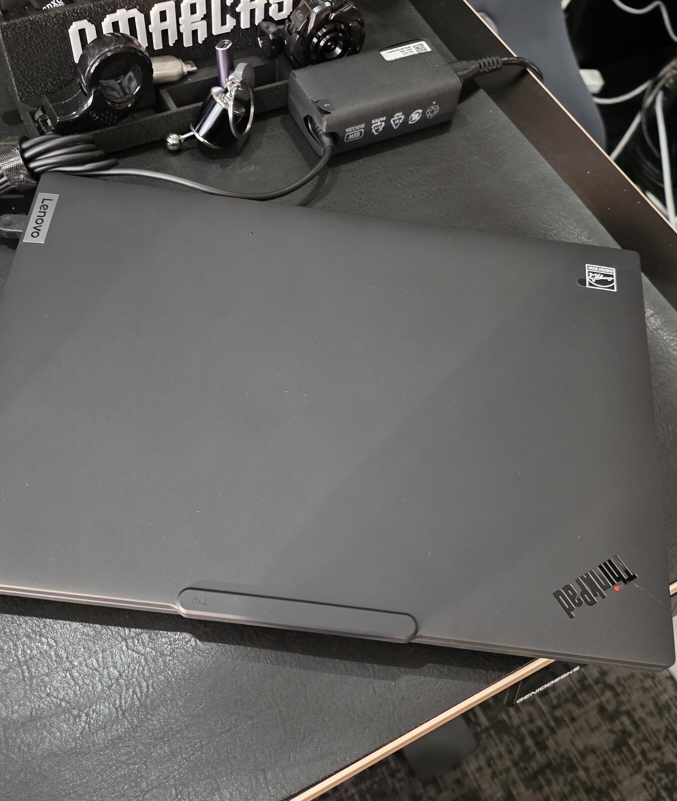 Thinkpad T14 Gen 6 fechado ao lado do carregador USB-C